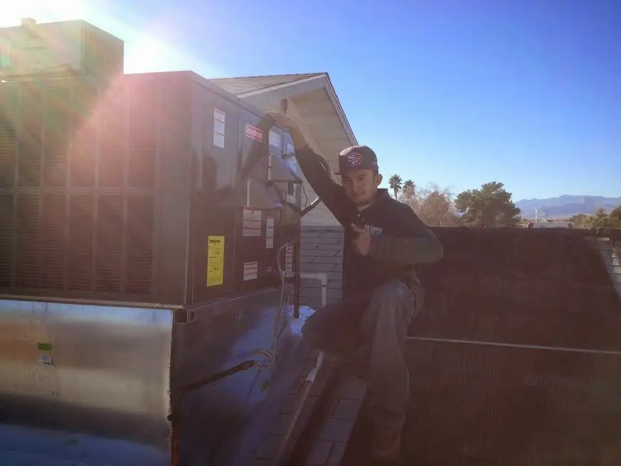 HVAC technician performing Air Duct Repair on a rooftop unit in Rawlins
